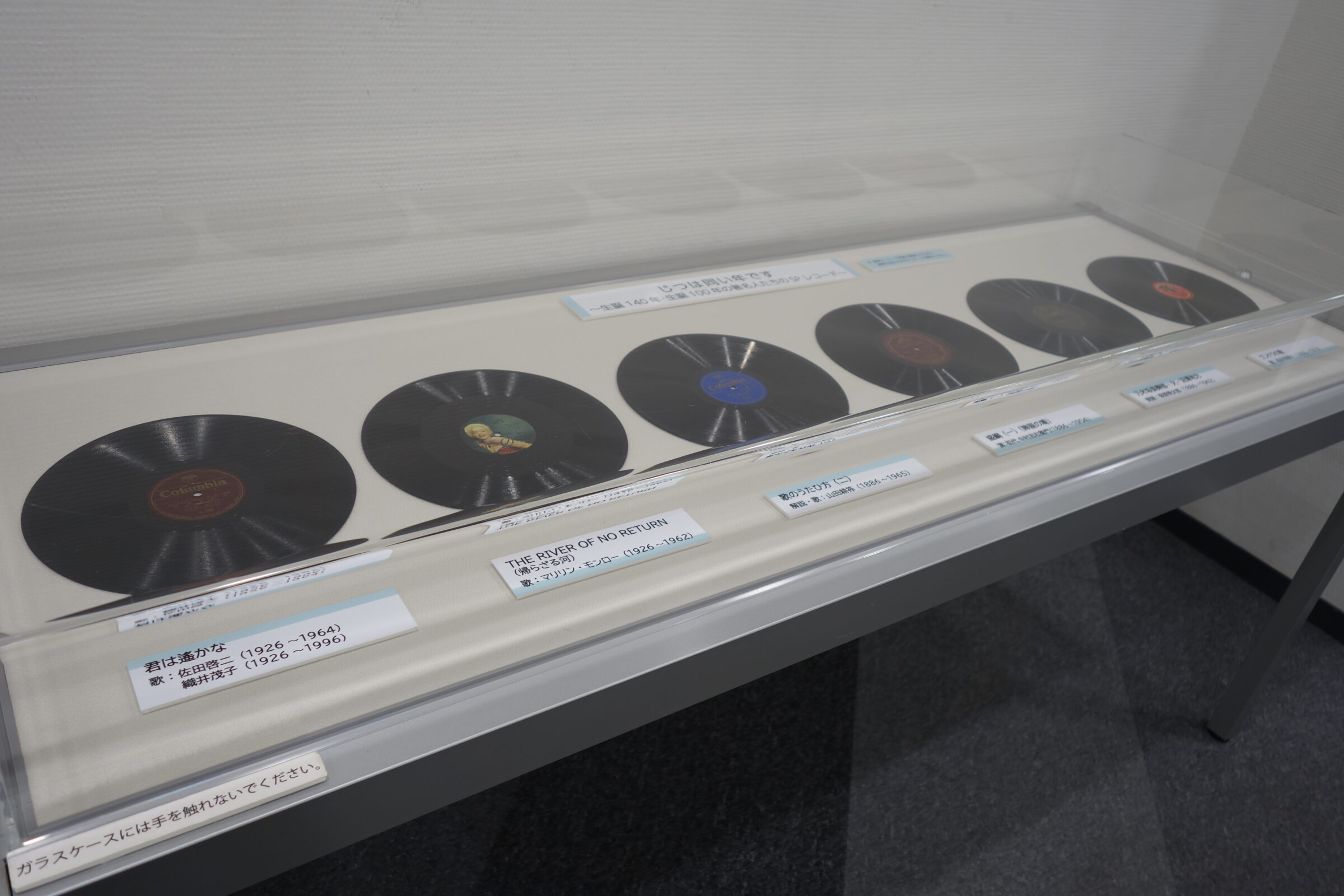 5階ギャラリー（廊下）の展示風景の写真、本文中①～⑥の6枚のSPレコードが展示してある。
